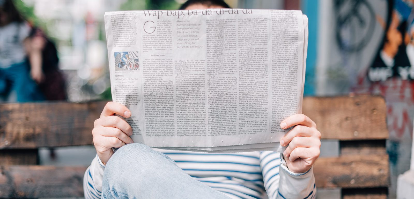 man sitting on bench reading newspaper